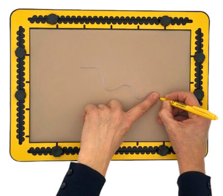 A raised wavy line is being drawn on a TactiPad. One hand holds a pen while the other hand touches and follows the raised line with the index finger.