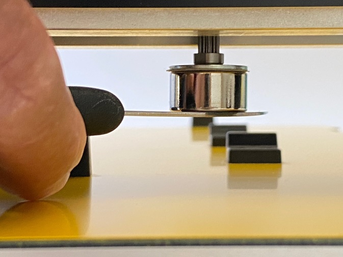 Close-up photo of the first step in adjusting the assembly using shims to set the line height; a blunt knife is used to hold the magnet in place